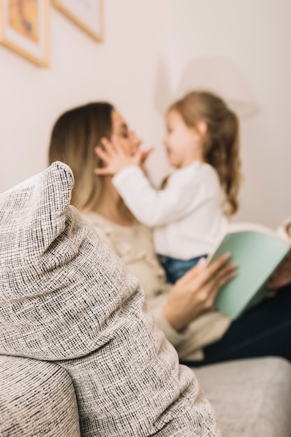 Blurred daughter and mother reading and having fun