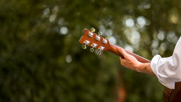 Blurred leaves and man playing guitar from behind shot