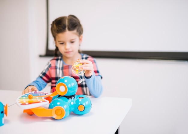 Blurred little girl holding cables in hand looking at electric toys