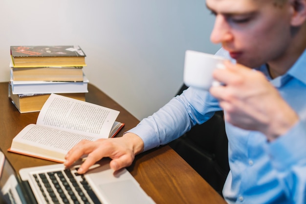 Blurred man drinking and using laptop