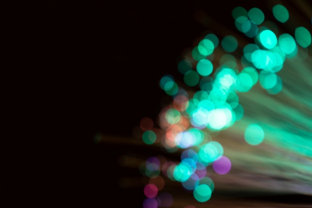 Blurred optical fiber lights on black screen