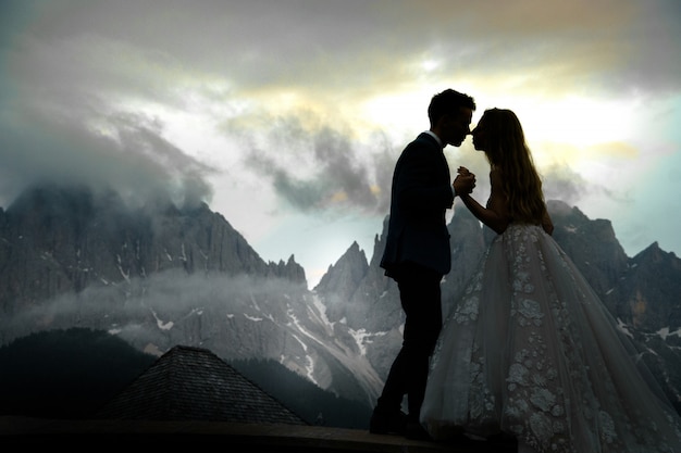 Blurred picture of kissing wedding couple standing before gorgeous mountain landscape 