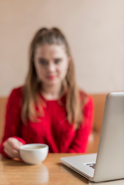 Blurred scene of woman with laptop and coffee cup