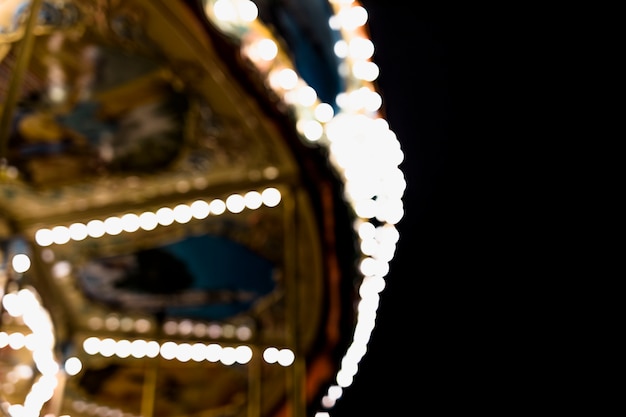 A blurry carousel at the amusement park against black backdrop