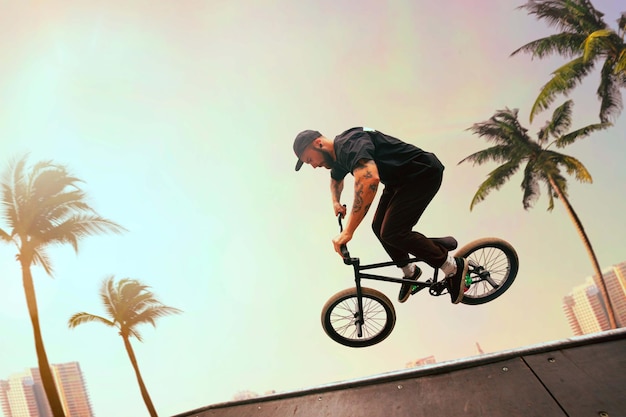 Free photo bmx rider is performing tricks in skatepark on sunset