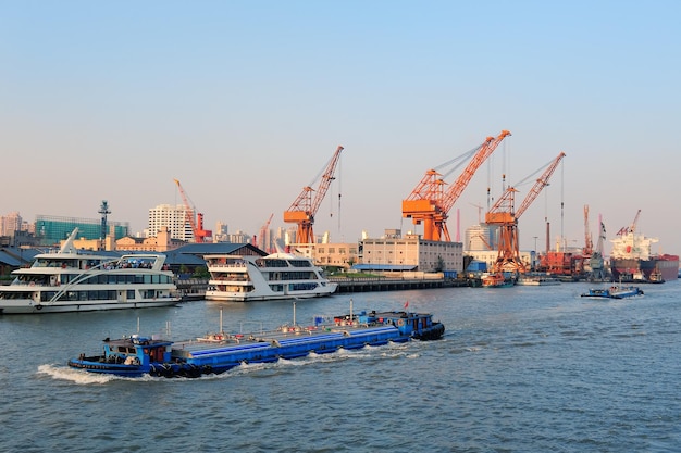 Free Photo boat in huangpu river with shanghai urban architecture and cargo crane