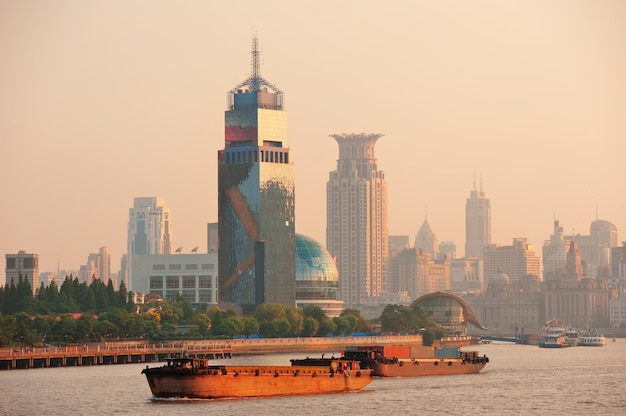 Boat in Huangpu River with Shanghai urban architecture at sunset