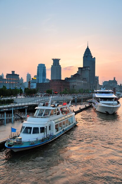 Boat in Huangpu River with Shanghai urban architecture at sunset