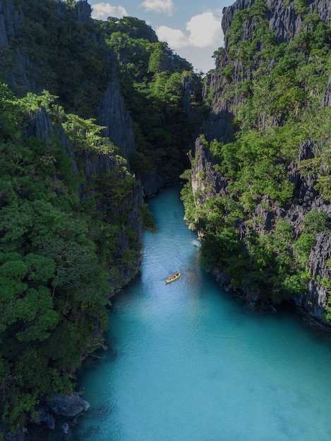 Free photo boat on the river surrounded by the cliffs covered in greens