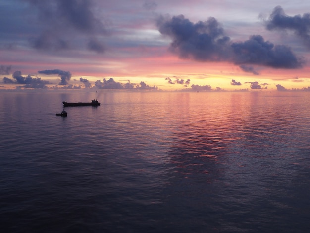 Boat on a sea under a cloudy sky during a beautiful colorful sunset in the evening