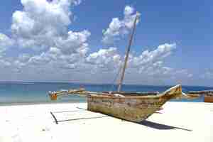 Free photo boat on the shore near the sea on a sunny day with cloudy sky in the background