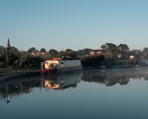 Boat on the water near the shore with buildings in the distance under a blue sky