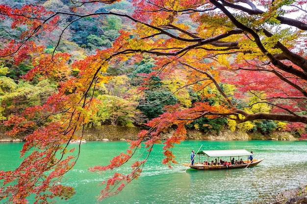 Free photo boatman punting the boat at river. arashiyama in autumn season along the river in kyoto, japan.