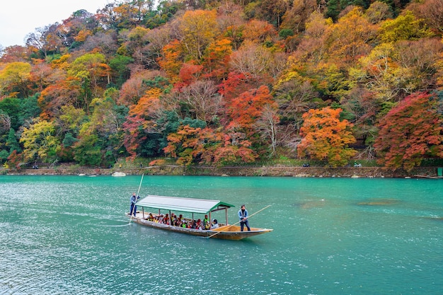 Free photo boatman punting the boat at river. arashiyama in autumn season along the river in kyoto, japan