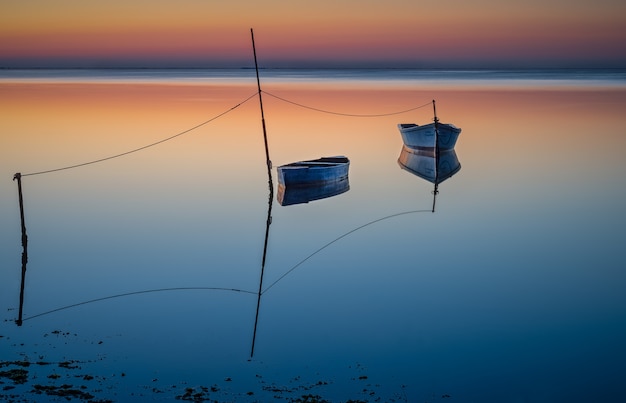 Free photo boats floating ob the water under the colorful sky