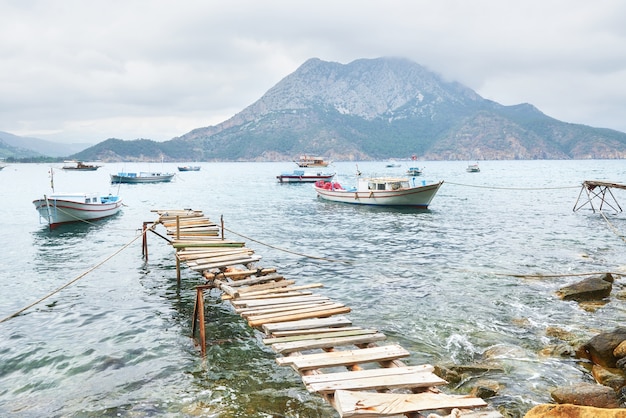 Boats near the broken pier, putting in a tranquil calm blue sea water.