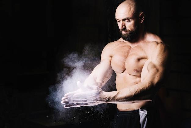 Bodybuilder rubbing hands with talcum powder