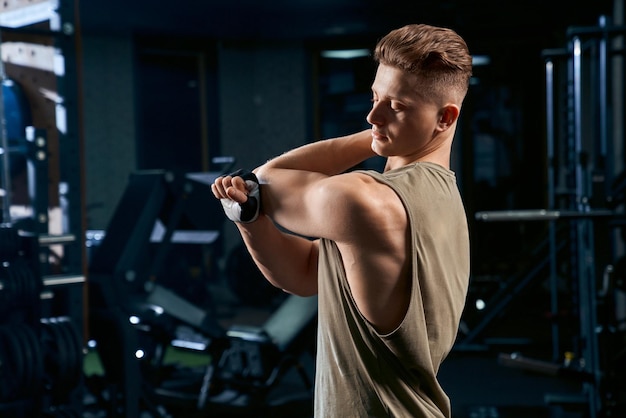 Bodybuilder stretching armsin gym