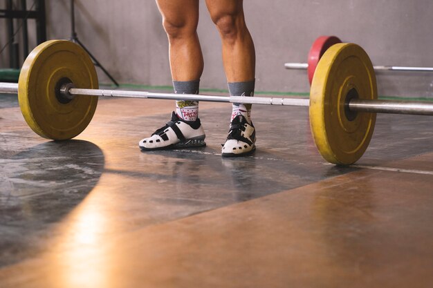 Bodybuilding concept with man standing in front of barbell