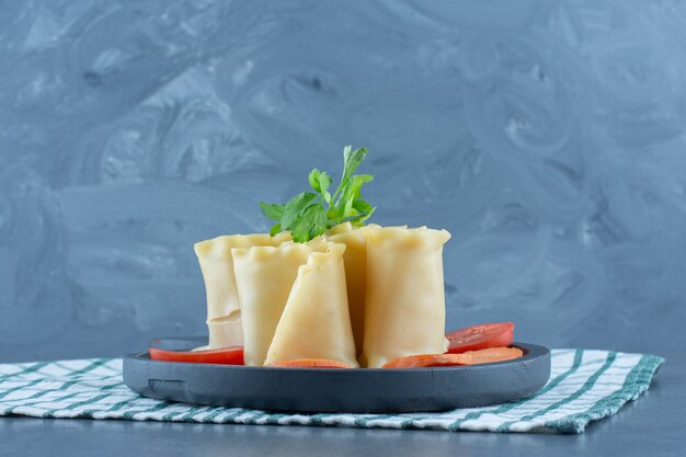 Boiled dough rolls and vegetables on dark board. 