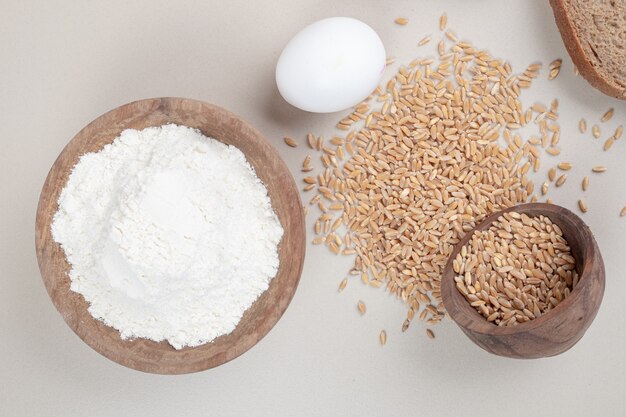 Boiled egg with oat grains and wooden bowl full of flour