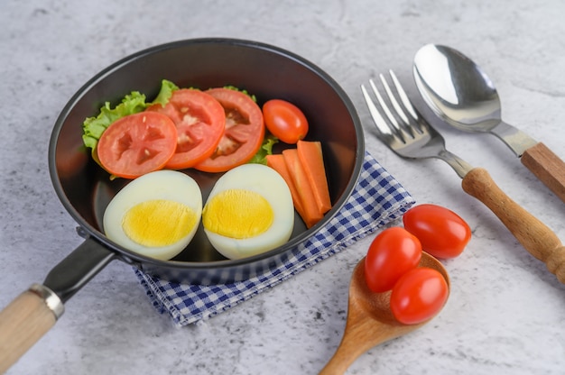 Free photo boiled eggs, carrots, and tomatoes on a pan with tomato on a wooden spoon.