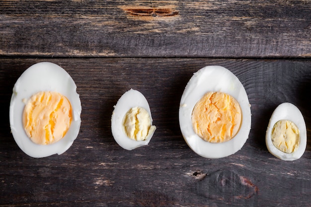 Free Photo boiled eggs cut in a half on a dark wooden background. top view.