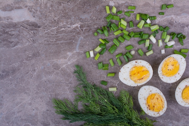 Free photo boiled eggs cut into half and served with herbs.