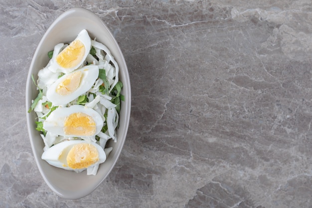 Free photo boiled eggs and fresh salad in ceramic bowl.