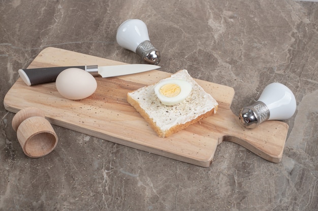 Boiled eggs and toast slice on cutting board with knife and spices. High quality photo