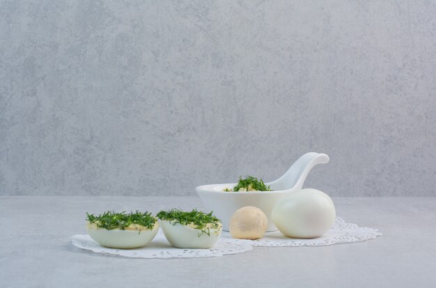 Boiled eggs with greens on white background.