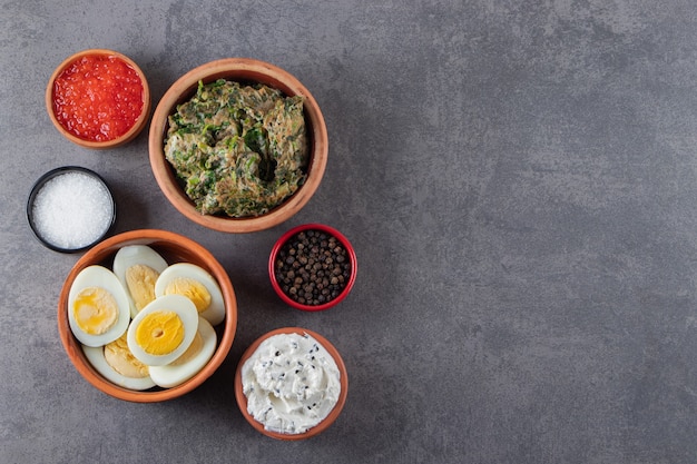 Boiled eggs with salt and caviar placed on a stone background