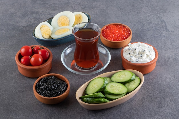 Boiled eggs with sausages and sliced cucumbers placed on stone table . 