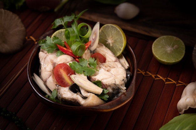 Free photo boiled fish infusion with tomatoes, mushrooms, coriander, spring onion and lemongrass in a bowl