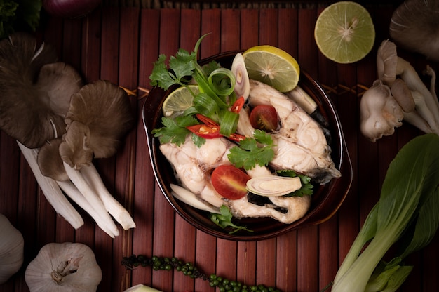 Free photo boiled fish infusion with tomatoes, mushrooms, coriander, spring onion and lemongrass in a bowl