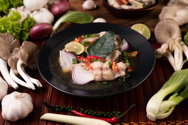 Boiled fish infusion with tomatoes, mushrooms, coriander, spring onion and lemongrass in a bowl