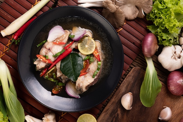 Free photo boiled fish infusion with tomatoes, mushrooms, coriander, spring onion and lemongrass in a bowl