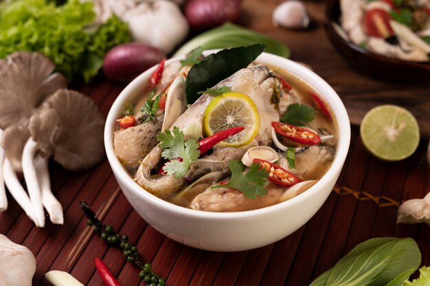 Boiled fish infusion with tomatoes, mushrooms, coriander, spring onion and lemongrass in a bowl