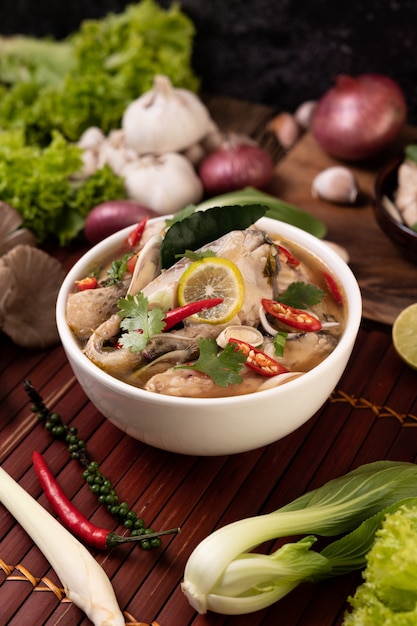 Free photo boiled fish infusion with tomatoes, mushrooms, coriander, spring onion and lemongrass in a bowl