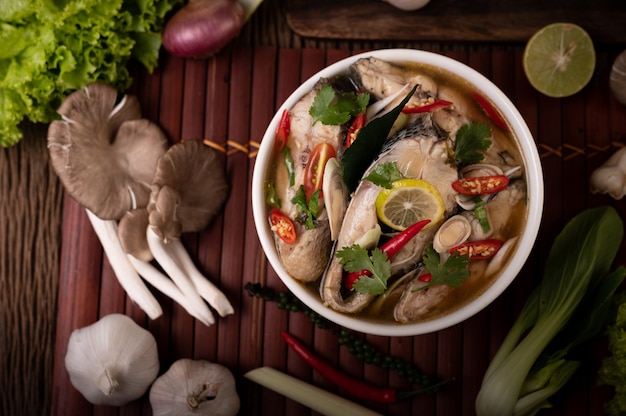 Free photo boiled fish infusion with tomatoes, mushrooms, coriander, spring onion and lemongrass in a bowl