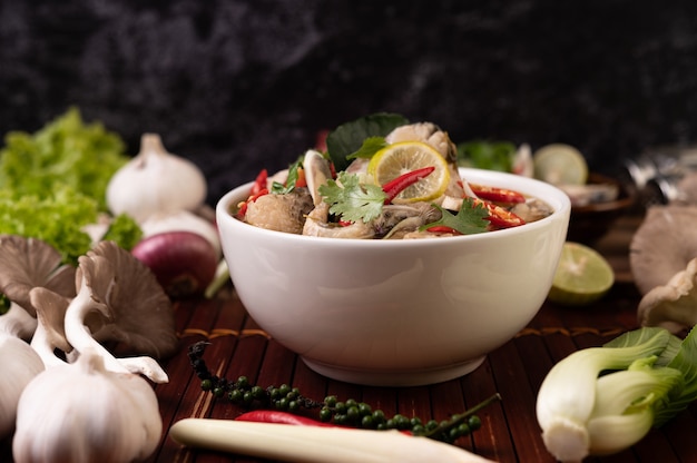 Free photo boiled fish infusion with tomatoes, mushrooms, coriander, spring onion and lemongrass in a bowl