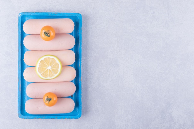 Free Photo boiled sausages decorated with lemon and tomatoes on blue plate. 