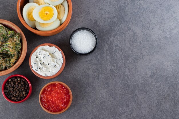 Boiled sliced eggs with spices placed on stone background .