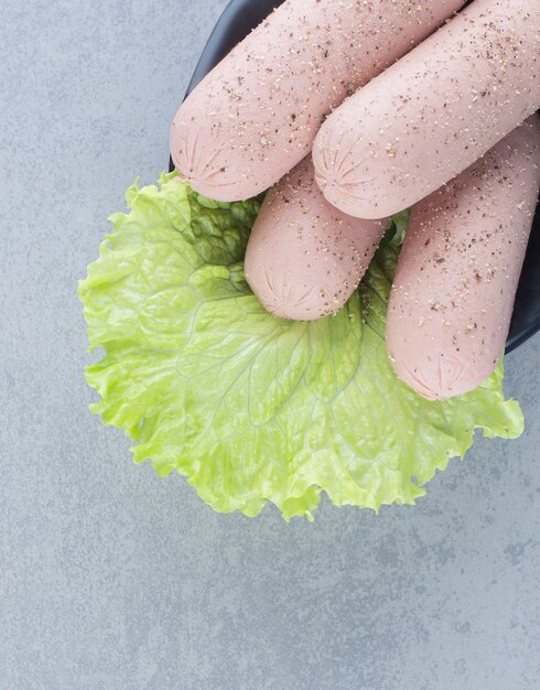 Boiled and spicy sausage with lettuce on grey background. 