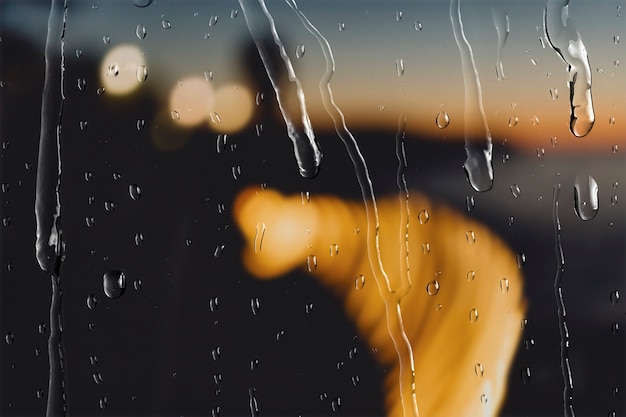 Free photo bokeh lights at night through window with rain drops