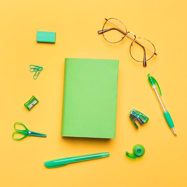 Free Photo book in colored cover surrounded by green school supplies