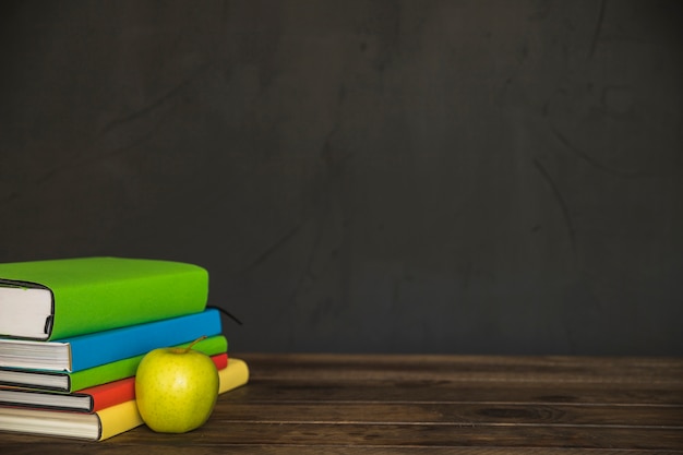 Book pile on table with apple