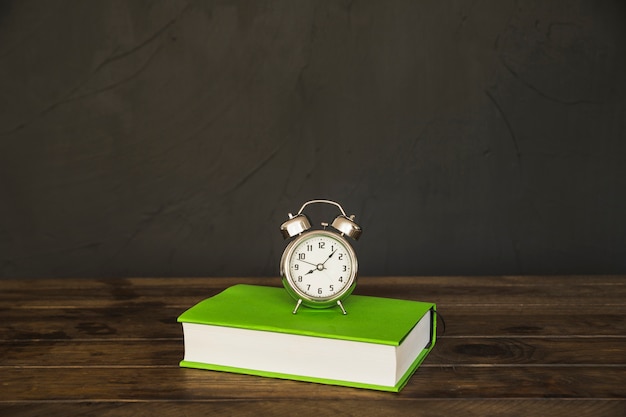 Book on table with alarm clocks