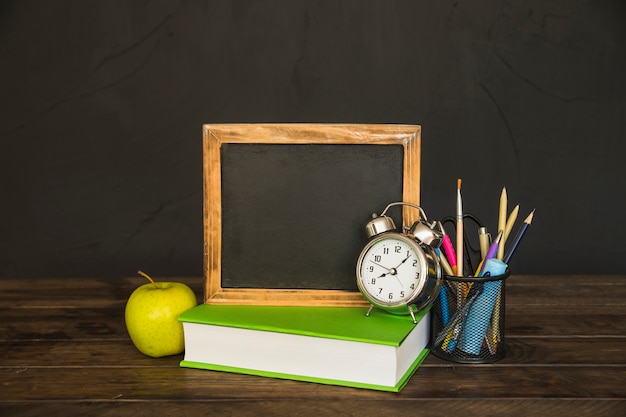 Free photo book with blackboard and alarm clocks on table with stationery