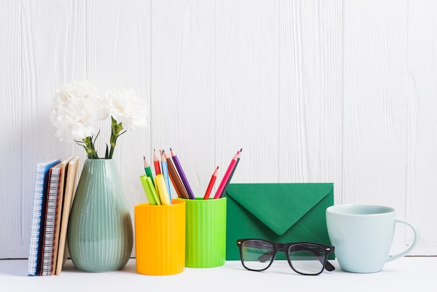 Free Photo books; vase; placeholder; envelope; eyeglasses and ceramics cup against wooden backdrop